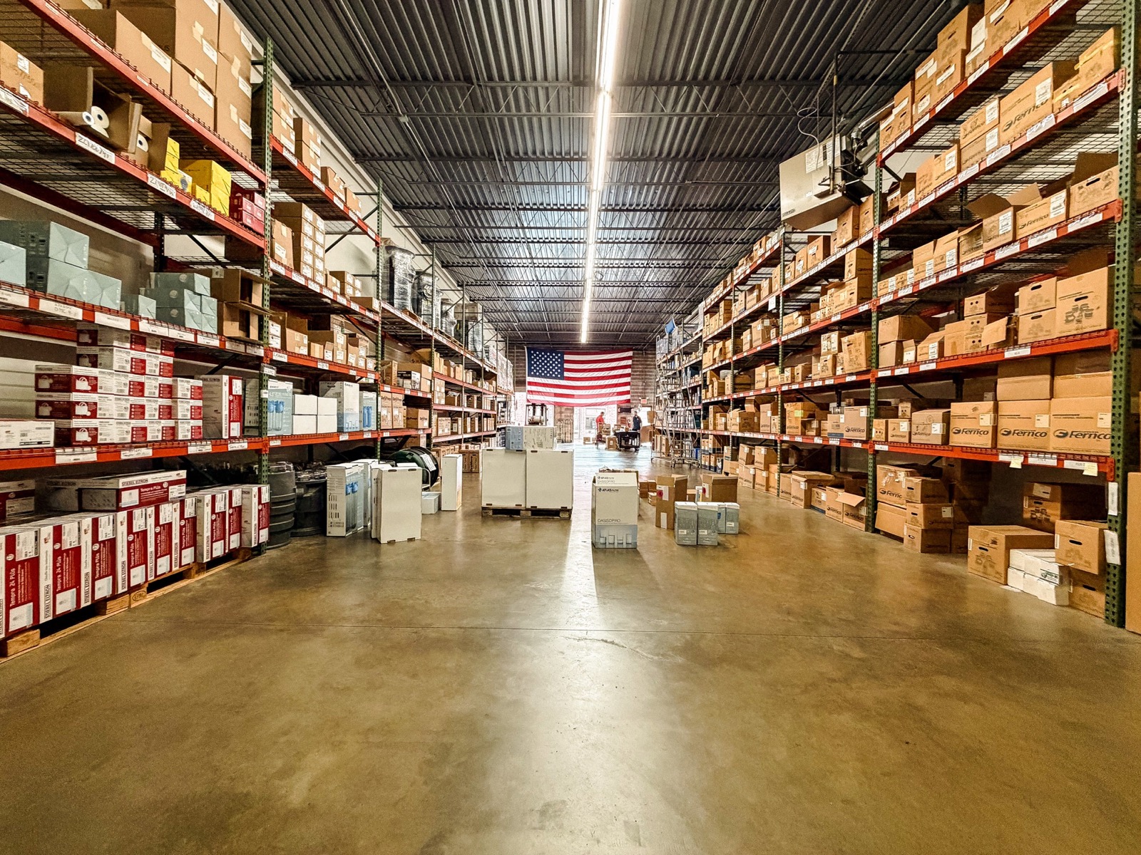 United Sales Agency warehouse aisle stocked with manufacturer products beneath an American flag